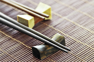 Traditional wooden chopsticks resting on a chopstick holder on a bamboo mat